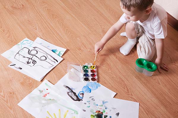 child using watercolors on laminate floor